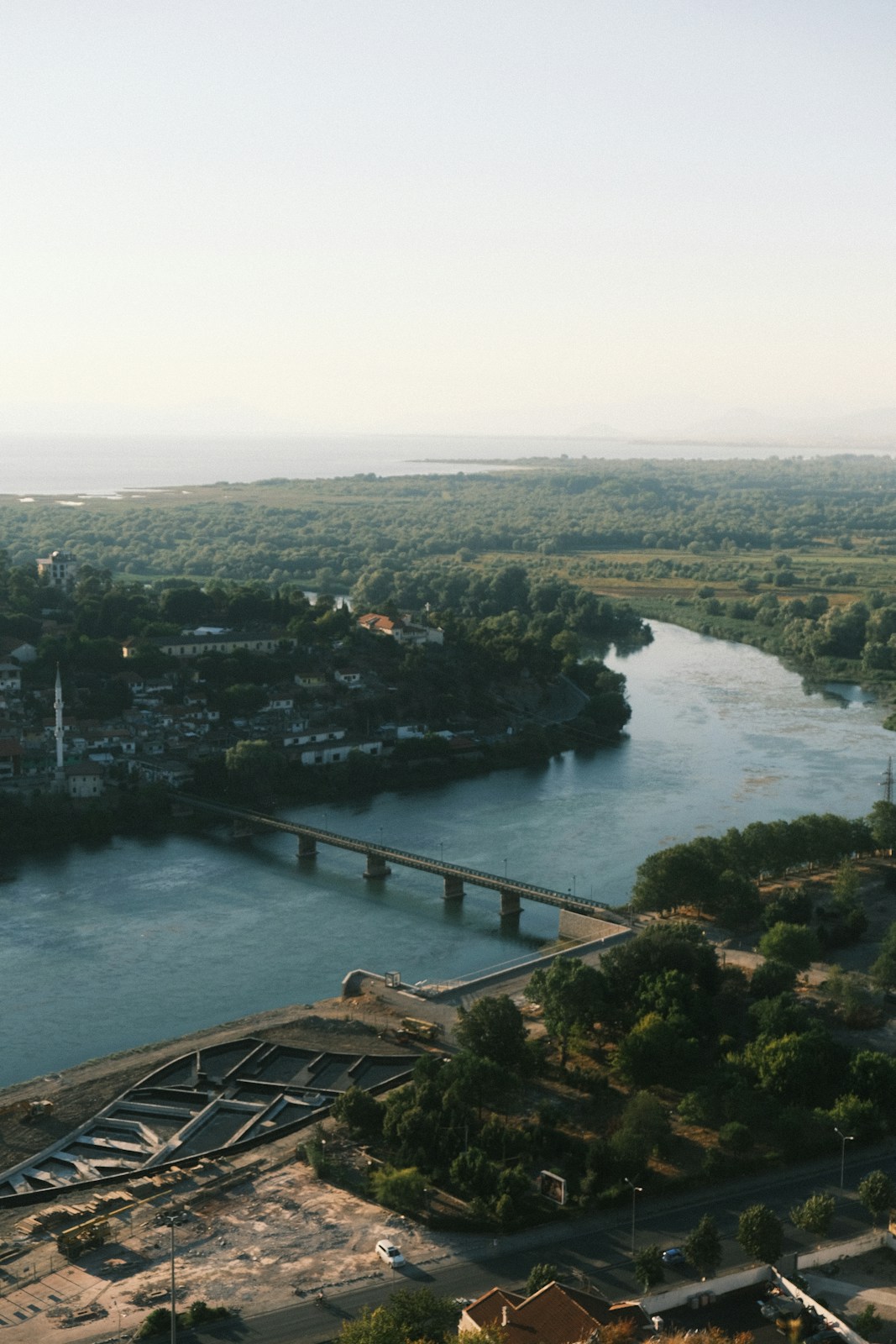A bridge crosses a wide river through a green landscape