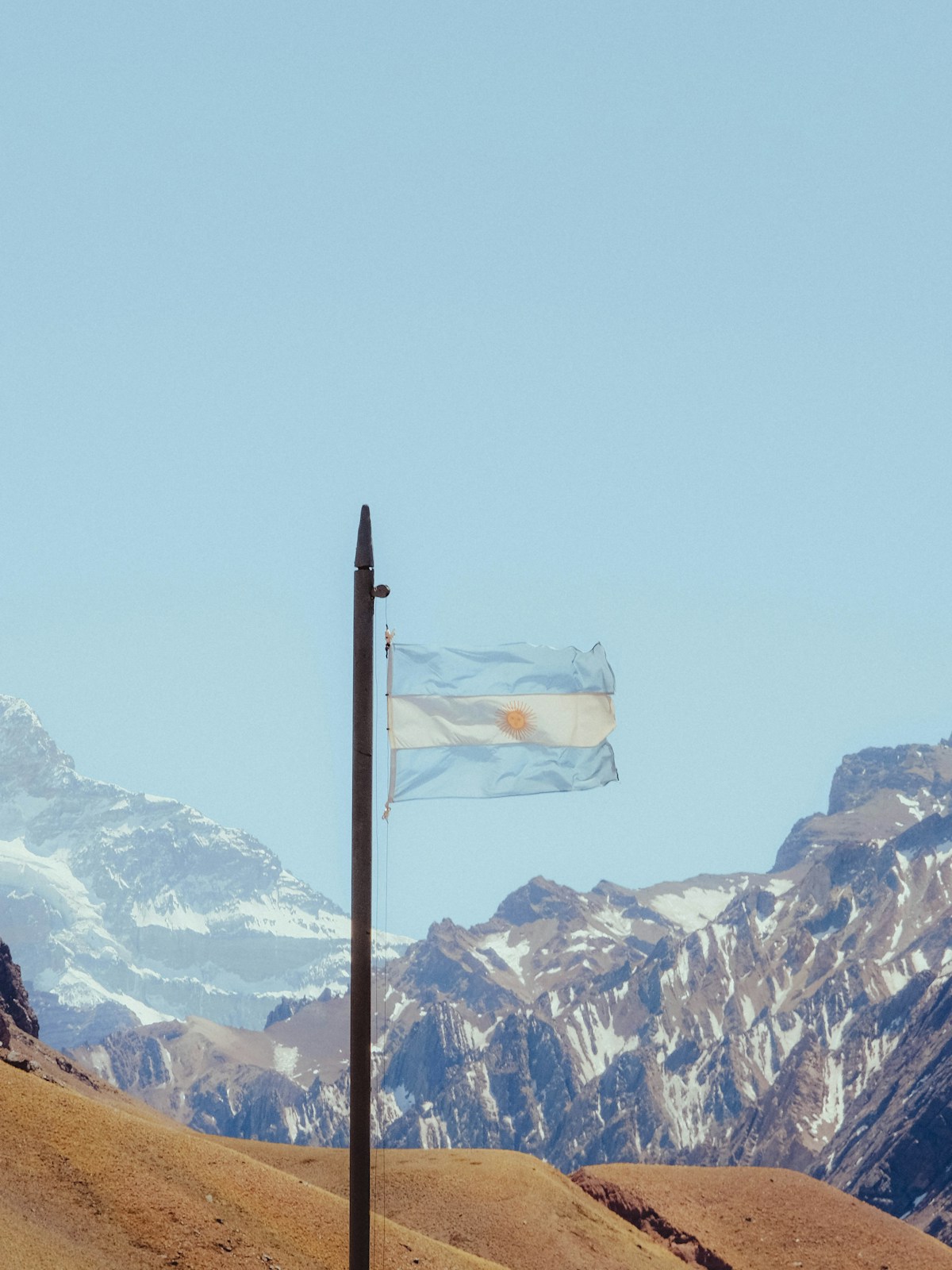 Argentinian flag waves in front of snowy mountains