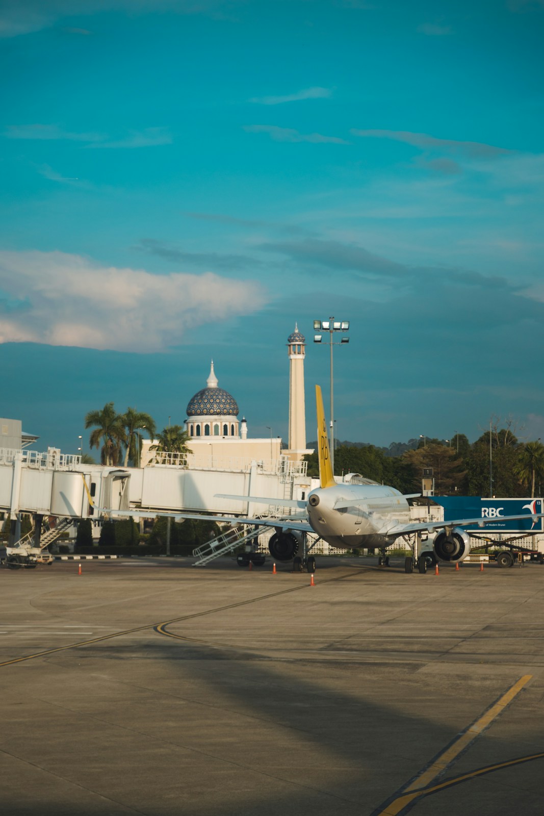 Airplane parked at airport terminal with mosque in background