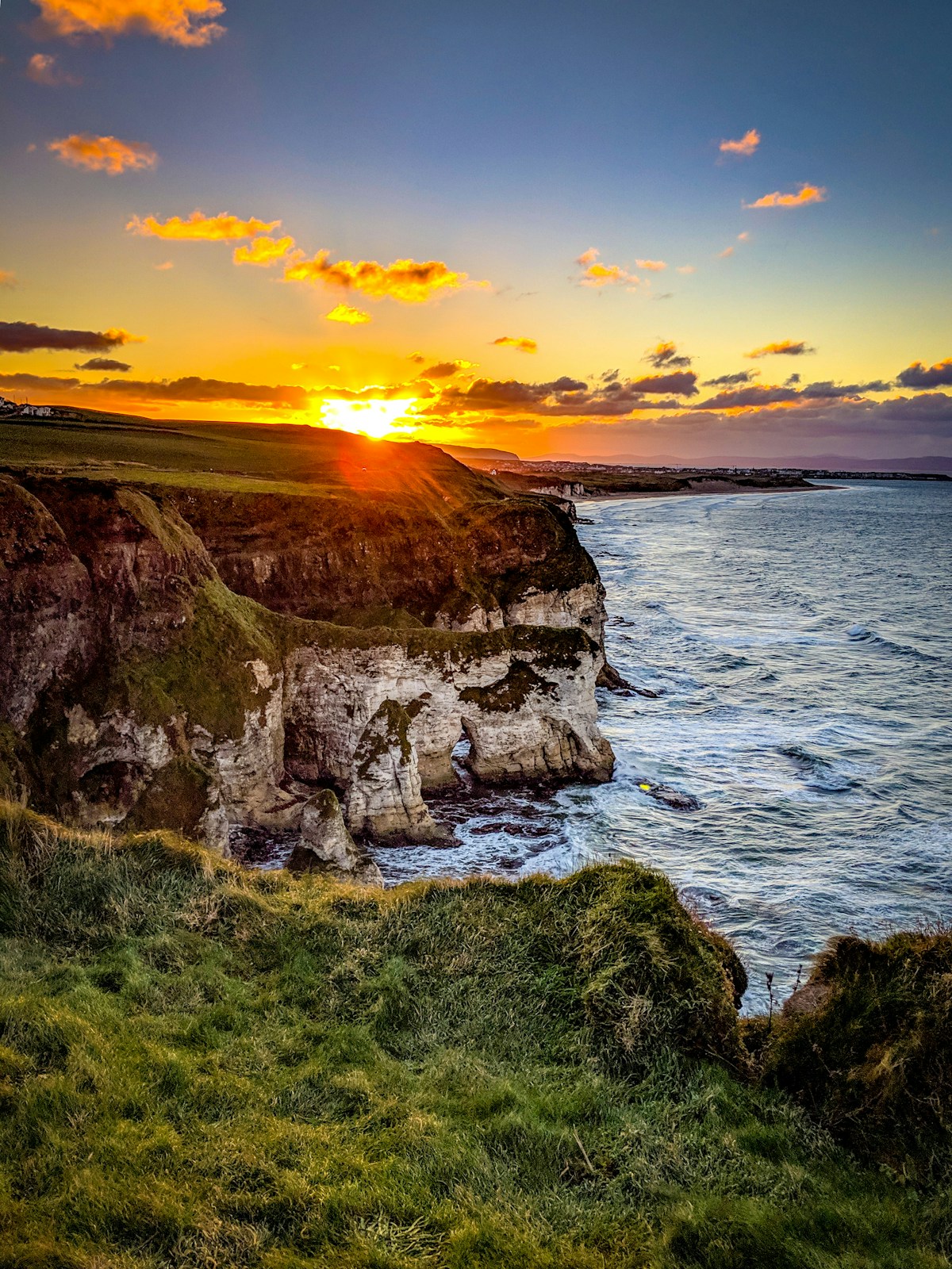 cliff beside body of water during sunset