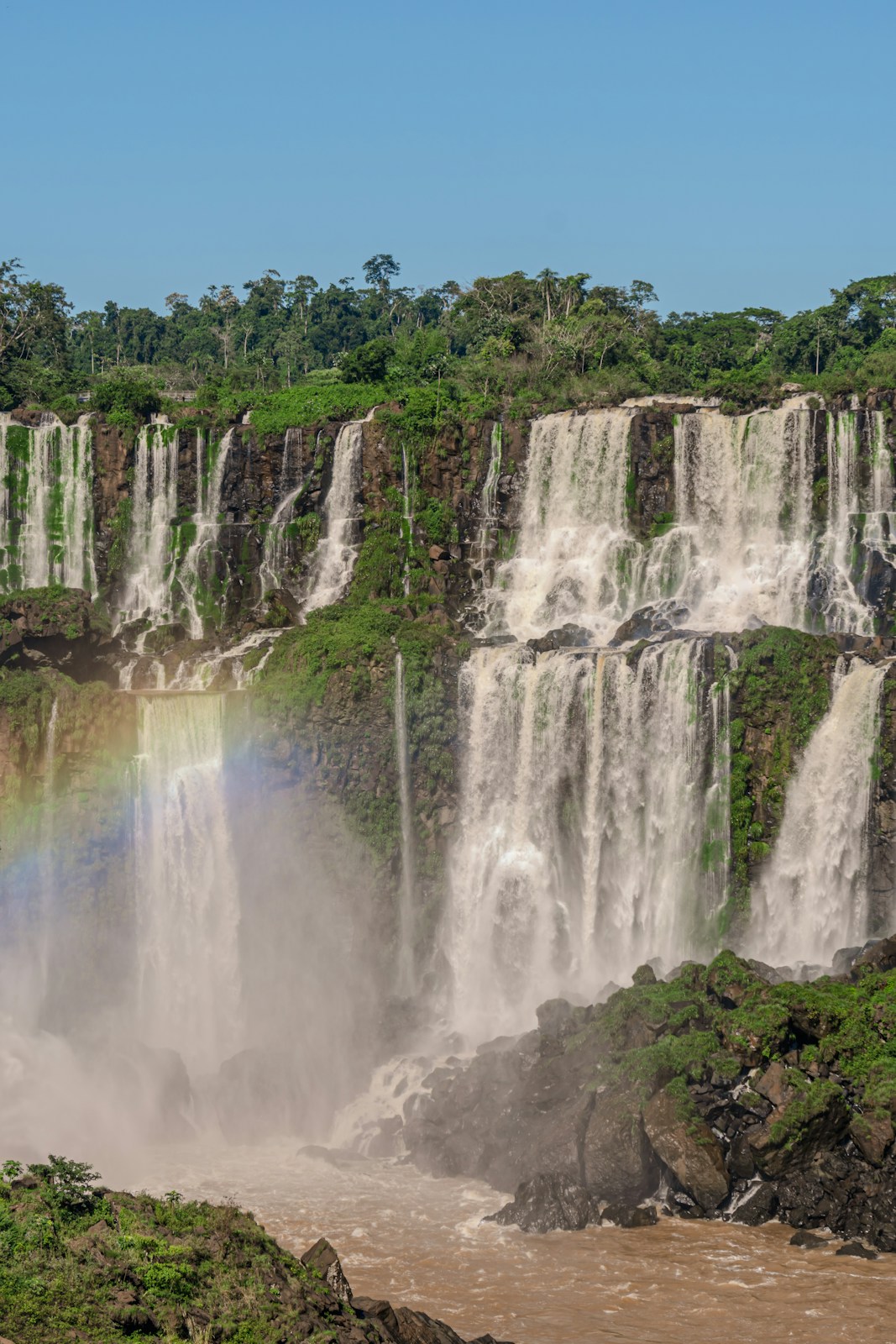 Majestic waterfalls cascade down lush green cliffs with a rainbow
