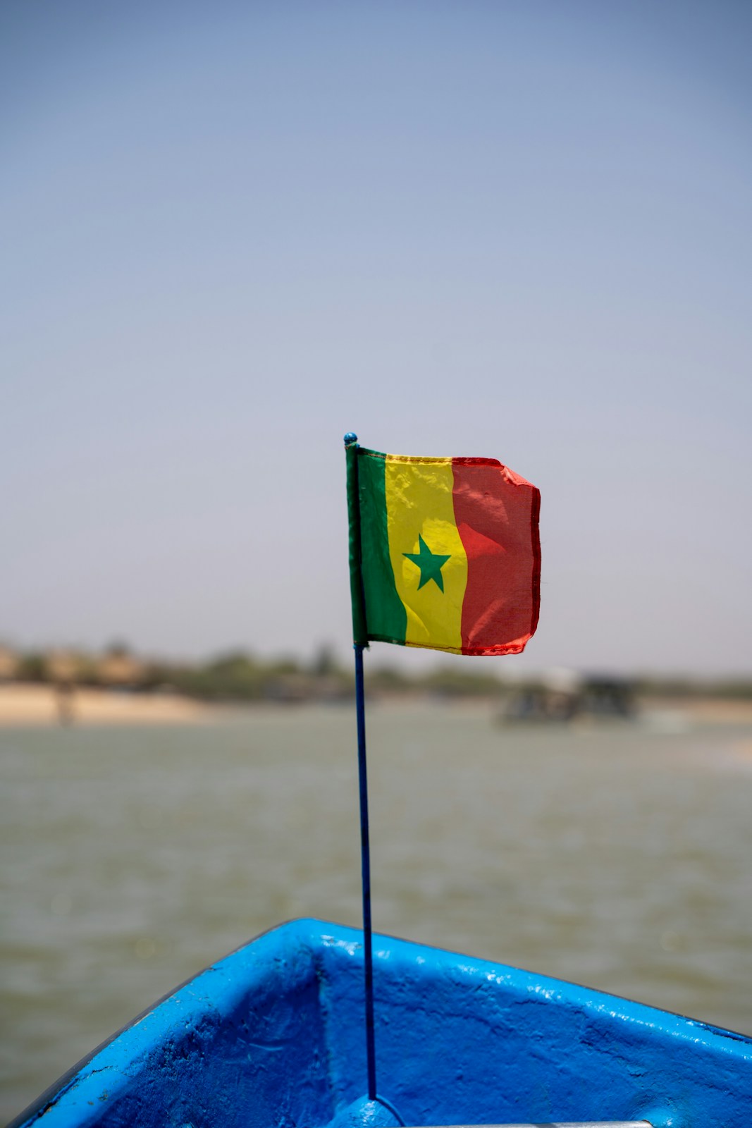Senegal flag flying on a blue boat over water