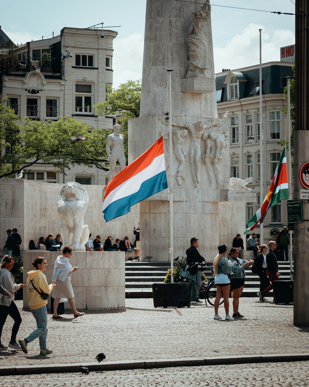 Dutch flag flies near monument with people walking