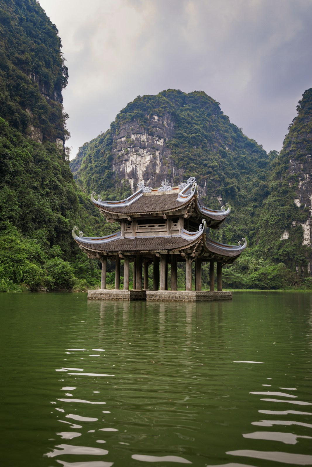 A pagoda in the middle of a lake surrounded by mountains