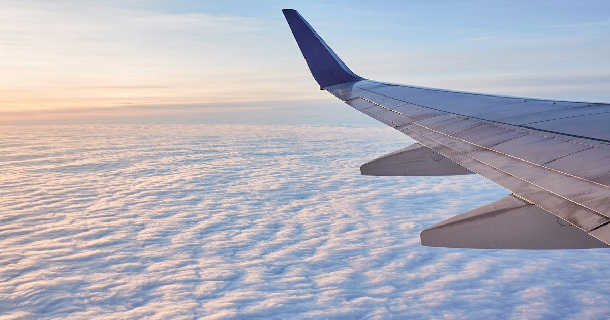 white and black airplane wing over white clouds during daytime